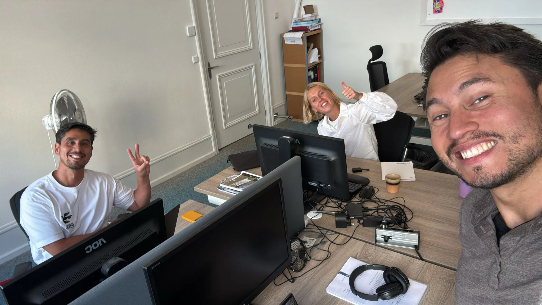 Keith, Veerle and Giorgio in the Polly office, smiling at the camera
